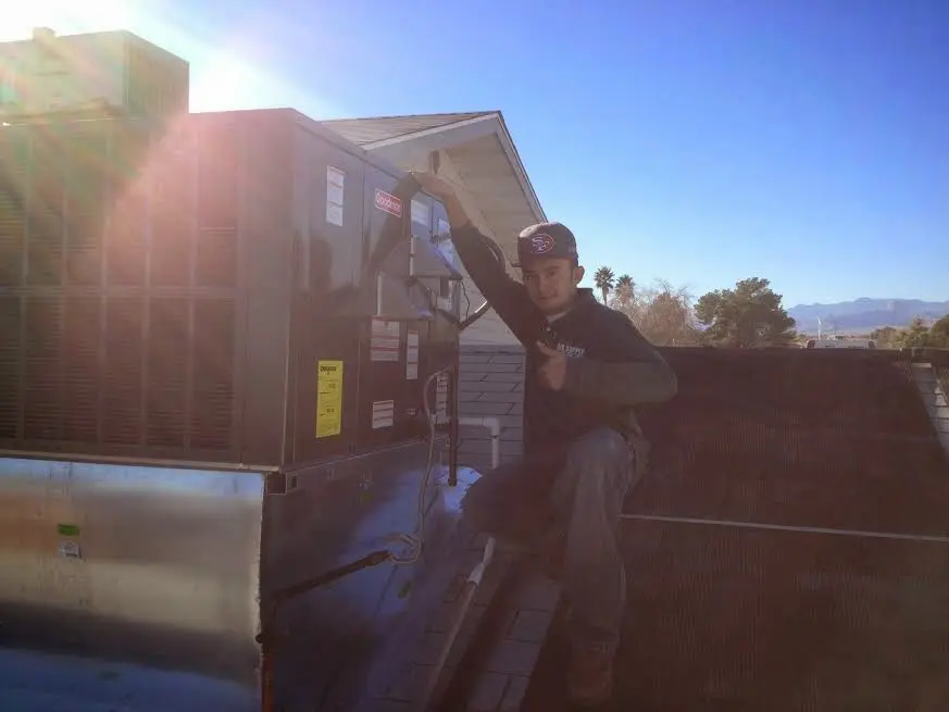 HVAC technician performing Heat Pump Repair on a rooftop unit in Biddeford